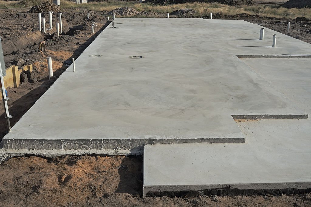 Concrete slab prepared for residential house construction with utility pipes within slab